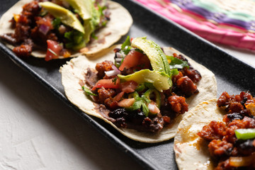 Mexican pork chorizo tacos with avocado and beans on white background