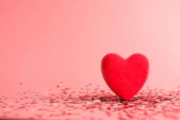 Fototapeta premium Valentine's Day background . red gloss heart with confetti on pink pastel background with copy space. wedding wallpaper.