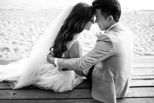 Sensual black and white photo of hugging newlyweds which sit near the river