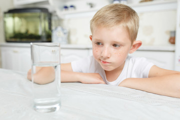 Fototapeta premium little boy in kitchen with glass of clean water