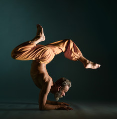 Old man with grey beard doing yoga, pilates, fitness training, stretching exercise, asana or...