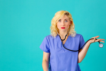 Close up studio portrait of a young female doctor or nurse wearing blue scrubs with hand out and...