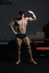 Fototapeta na wymiar Bodybuilder Performing Front Biceps Pose In Gym