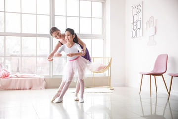 Little ballerina training with coach in dance studio