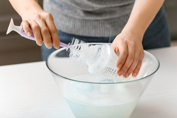 Woman cleaning baby bottle at home, closeup