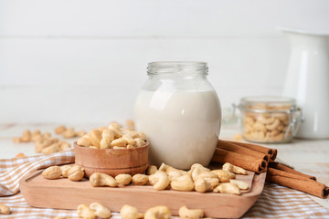 Jar of cashew milk with nuts on wooden table