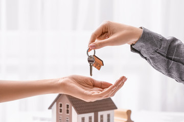 Real estate agent giving a key from new house to client in office