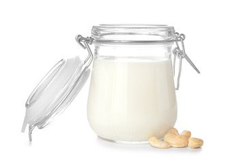 Jar of cashew milk with nuts on white background