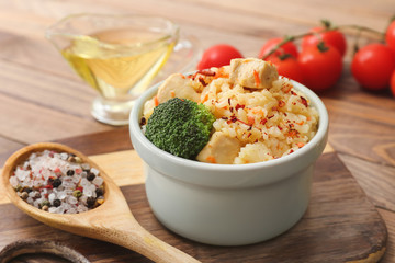 Bowl with tasty rice, chicken and spices on table
