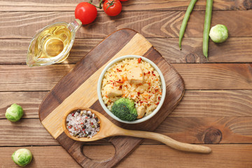 Bowl with tasty rice, chicken and vegetables on table