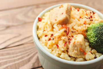 Bowl with tasty rice and chicken on table, closeup