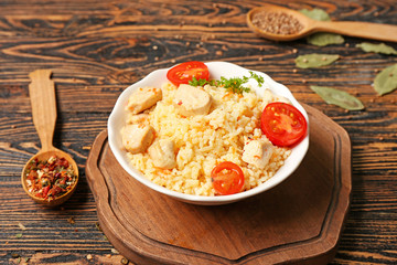 Bowl with tasty rice and chicken on table