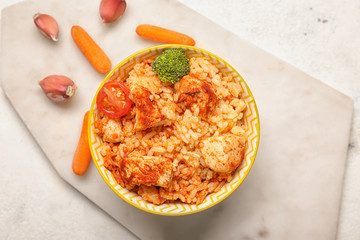 Bowl with tasty rice, chicken and vegetables on white background