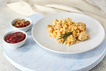 Plate with tasty rice and chicken on table