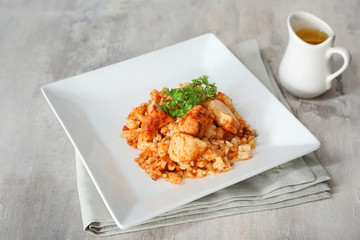 Plate with tasty rice and chicken on grey background