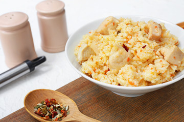Bowl with tasty rice and chicken on table