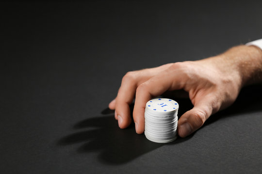 Male hand with chips for gambling games on dark background
