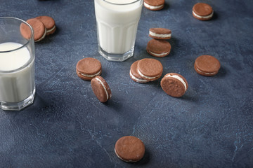 Tasty chocolate cookies with milk on dark background