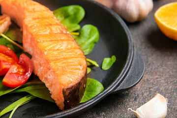 Frying pan with tasty cooked salmon on table