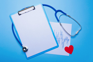 Stethoscope, heart, clipboard and cardiogram on color background