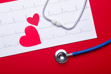 Stethoscope, hearts and cardiogram on color background
