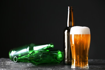 Glass of beer and bottles on table. Concept of alcoholism