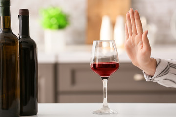 Woman refusing to drink wine at home. Concept of alcoholism