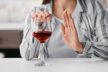 Woman refusing to drink wine at home. Concept of alcoholism