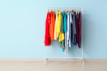 Rack with modern clothes near color wall