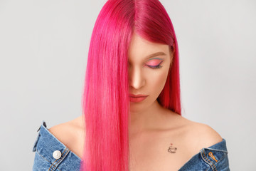 Beautiful young woman with unusual hair color on light background