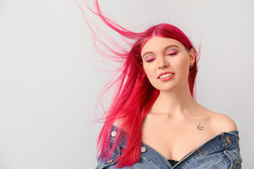 Beautiful young woman with unusual hair color on light background