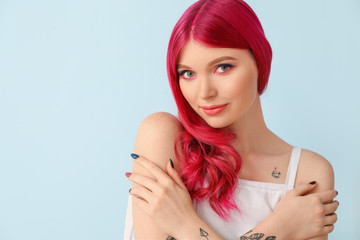 Beautiful young woman with unusual hair on color background