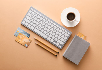 Credit cards with computer keyboard, cup of coffee and stationery on color background. Concept of online banking