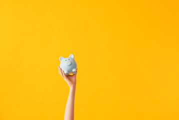 Female hand with piggy bank on color background