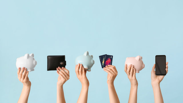 Female hands with piggy banks, credit cards, wallet and mobile phone on color background. Concept of online banking
