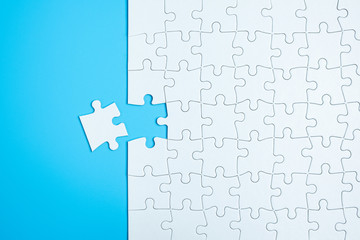 Blue background made from white jigsaw puzzle pieces and place for your content