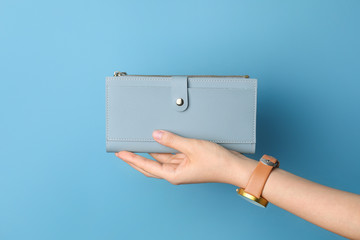 Female hand with wallet on color background