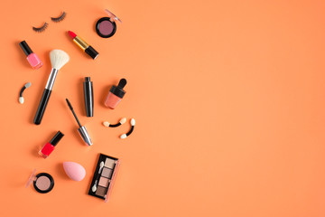 Makeup products and cosmetics on pastel orange background. Flat lay, top view. Beauty blog banner template.