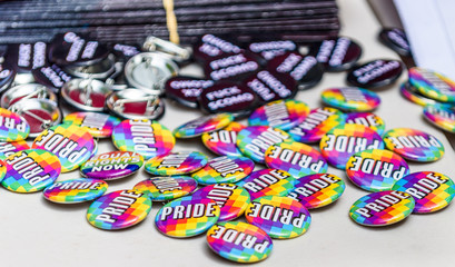 A pile of 'Pride' campaign buttons or badges are scattered on a table at a religious discrimination political protest