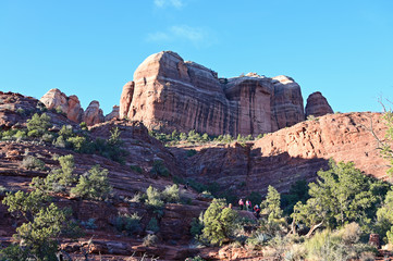 Fototapeta na wymiar Distant hikers on Cathedral Rock Trail near Sedona, Arizona in early morning on clear winter day.