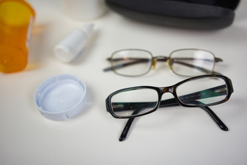 Glasses on white counter with various eye care products. Flat lay of medical supplies for vision care