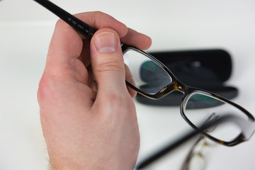 Hand holding eye glasses to put them on. First person human hand putting on spectacles for sight