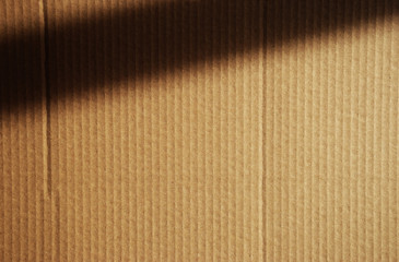 Brown Kraft cardboard vertical texture with a dark sun shadow over the top corner
