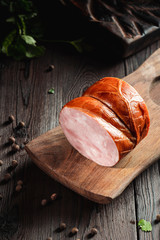 Smoked ham with herbs and spices on wooden rustic dark board