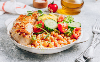 Healthy vegetable buddha bowl lunch with grilled chicken and chickpeas, cucumber, tomato and avocado on light gray background. Zero waste concept. Selective focus