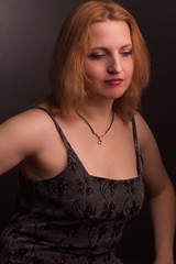 Naklejka premium portrait of large blonde model in a black dress on a dark background in the Studio