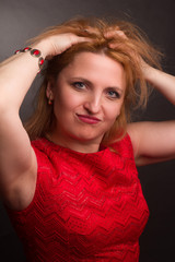 portrait of large blonde model in a red dress on a dark background in the Studio