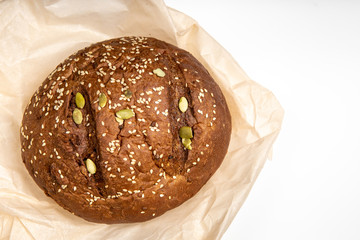 Tasty fresh baked loaf of dark bread with sesame seeds on white background