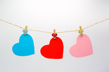 Colorful cutting paper hearts hanging rope with wooden clips isolated on white background for Happy Valentine's Day