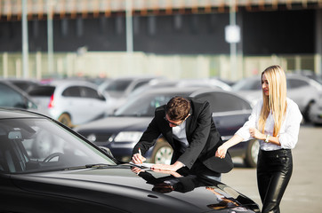 Happy young couple chooses and buying a new car for the family